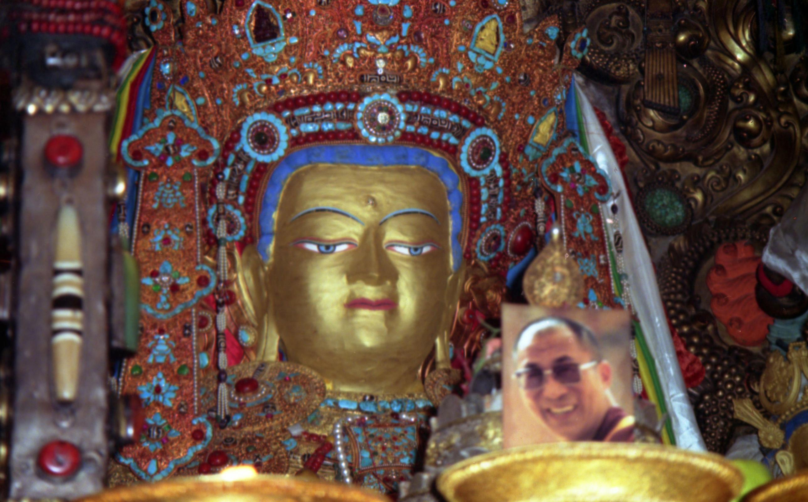 Tibet Lhasa 02 12 Jokhang Inside Jowo Shakyamuni The Chapel of Jowo Shakyamuni is the most important shrine in Tibet, housing a 1.5m sitting image of Shakyamuni at the age of 12. It is supposedly one of only three made during his lifetime. It was a gift from the Chinese Princess Wencheng to her husband King Songtsen Gampo. The Jowo sits on a majestic massive three-tiered stone platform. Two silver-plated dragons presented by the Chinese emperor entwine the ornate pillars that support an intricate double canopy over the Jowo. An ornate crown of coral, turquoise, diamonds, rubies, and other precious gems, sits on the Jowo�s head. Although there�s no photography allowed, here�s a photo from my 1993 trip. Note the photo of the current Dalai Lama, allowed in 1993 in a period of religious tolerance.